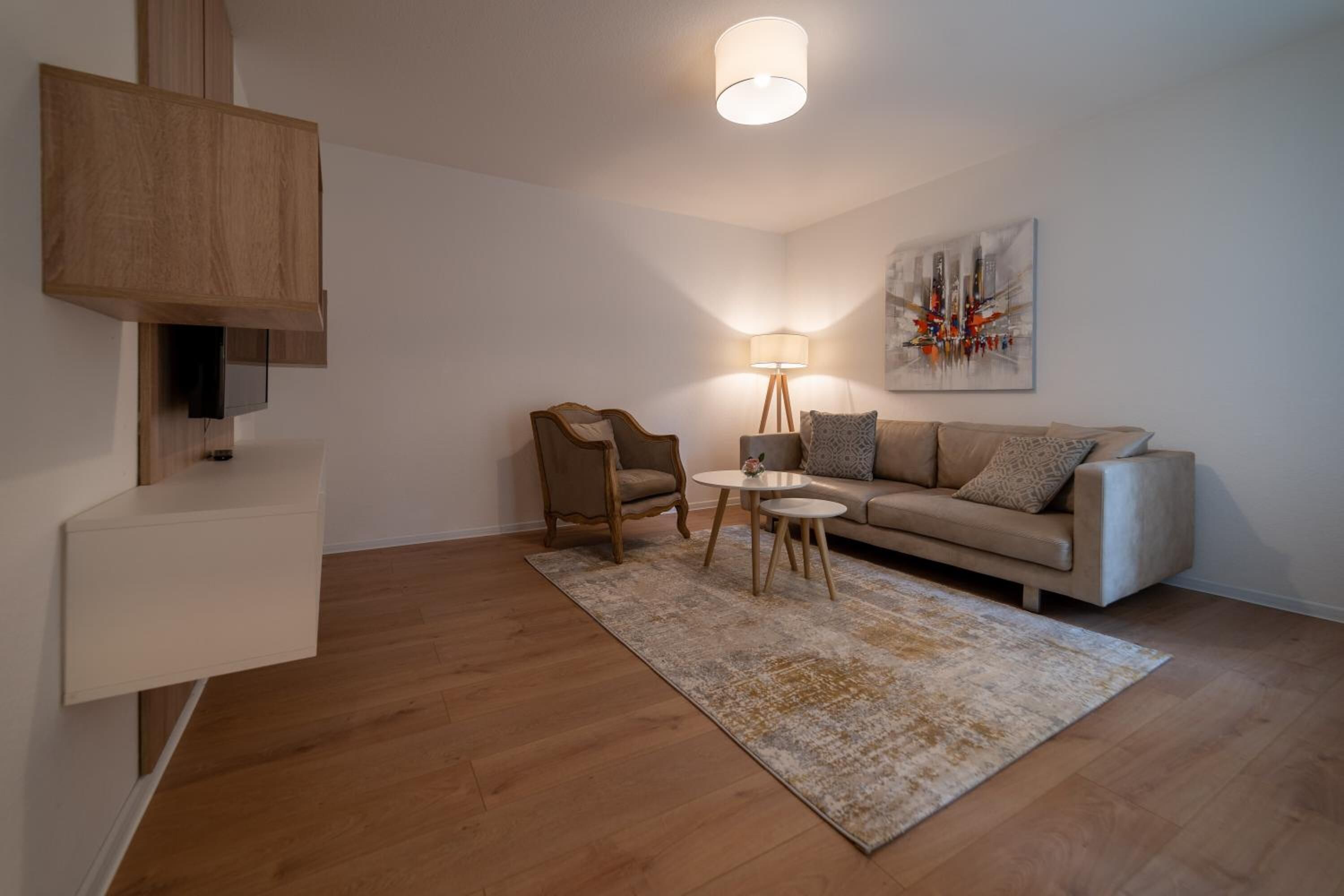 Ein modernes Wohnzimmer mit einer Couch, zwei Sesseln, einem Couchtisch, einer Lampe und einem Bild an der Wand.