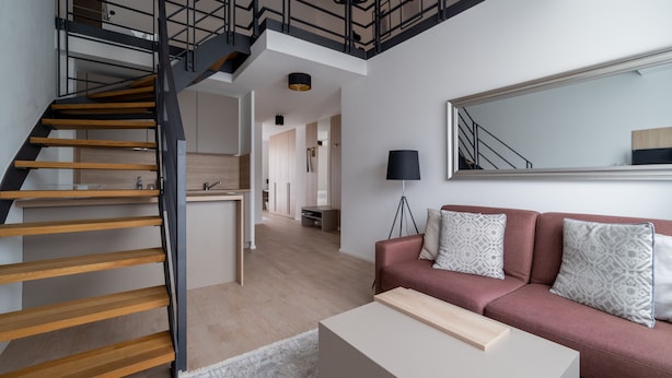 A modern living room with a staircase, a sofa, and a large mirror. - Aparthotel Cosy (Stuttgart)