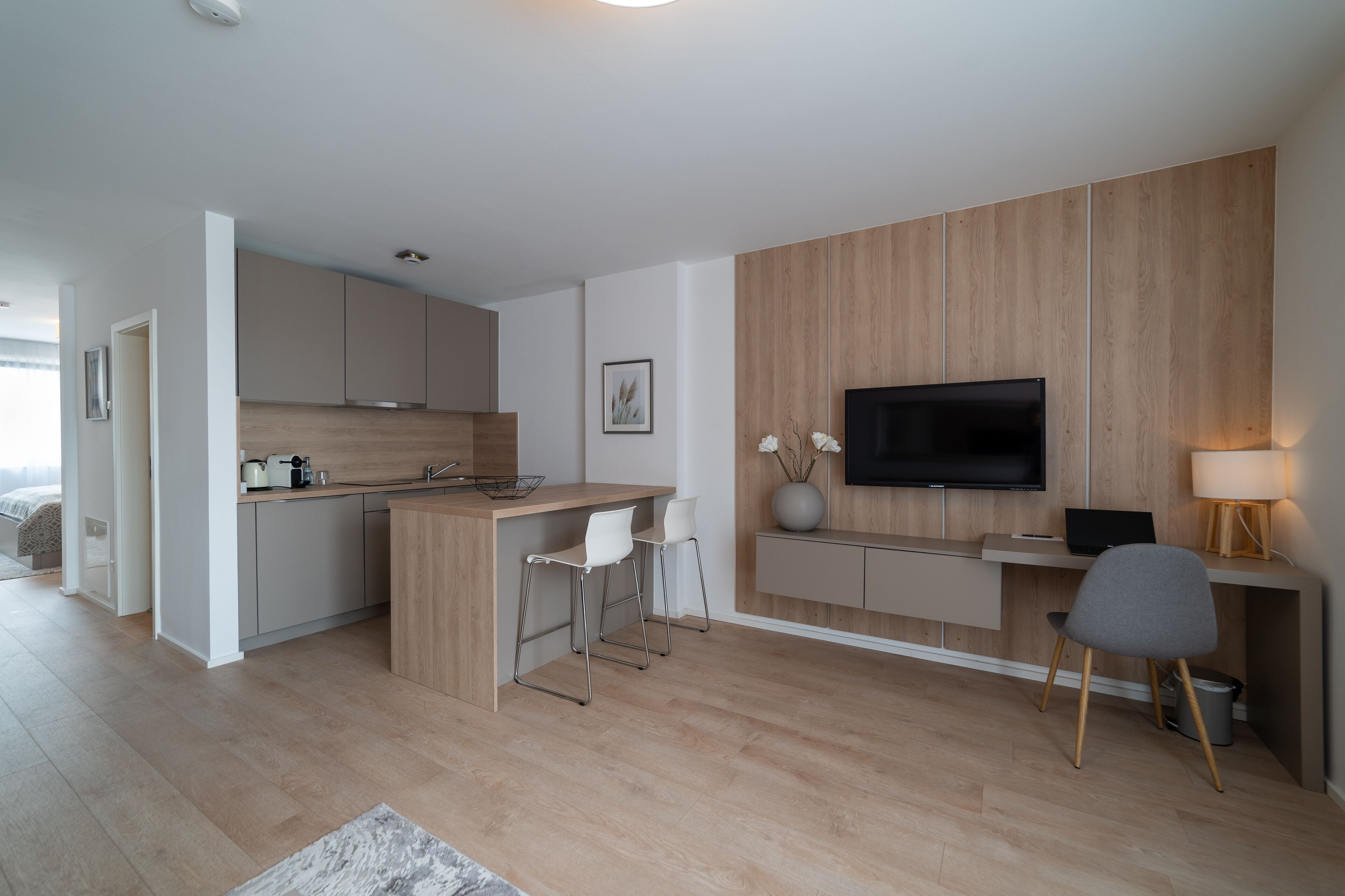 Eine moderne Küche mit einer Holztheke, Barhocker, einem Flachbildfernseher und einem Schreibtisch mit Lampe.