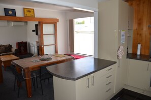 Ett kompakt kök med ett matbord i trä, en inbyggd köksö och utsikt mot omgivningen.