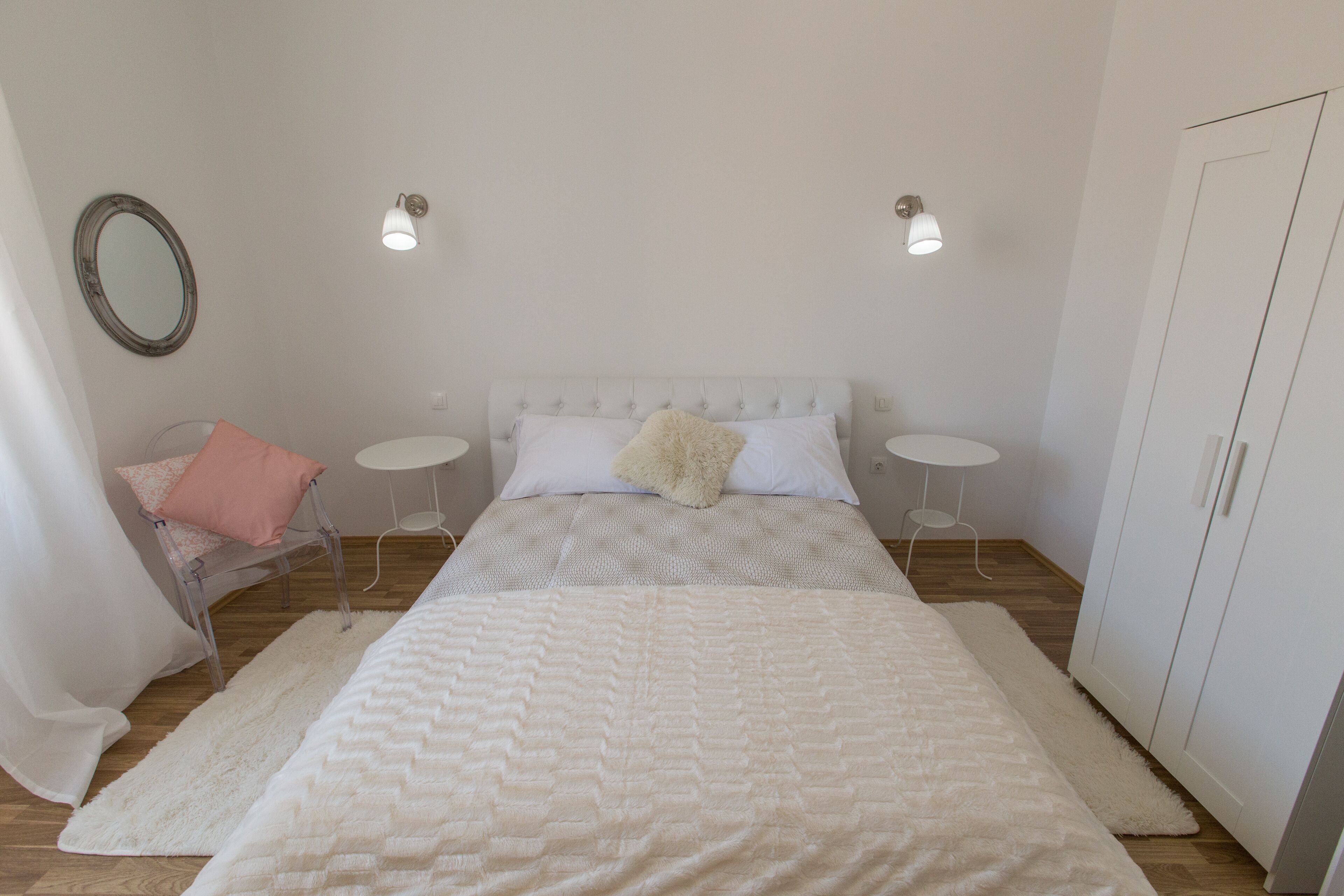 A bedroom with a bed, two bedside tables, a wardrobe, a mirror, and a chair.