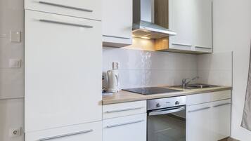 Una cocina moderna con armarios blancos, un lavamanos de acero inoxidable y un horno empotrado.