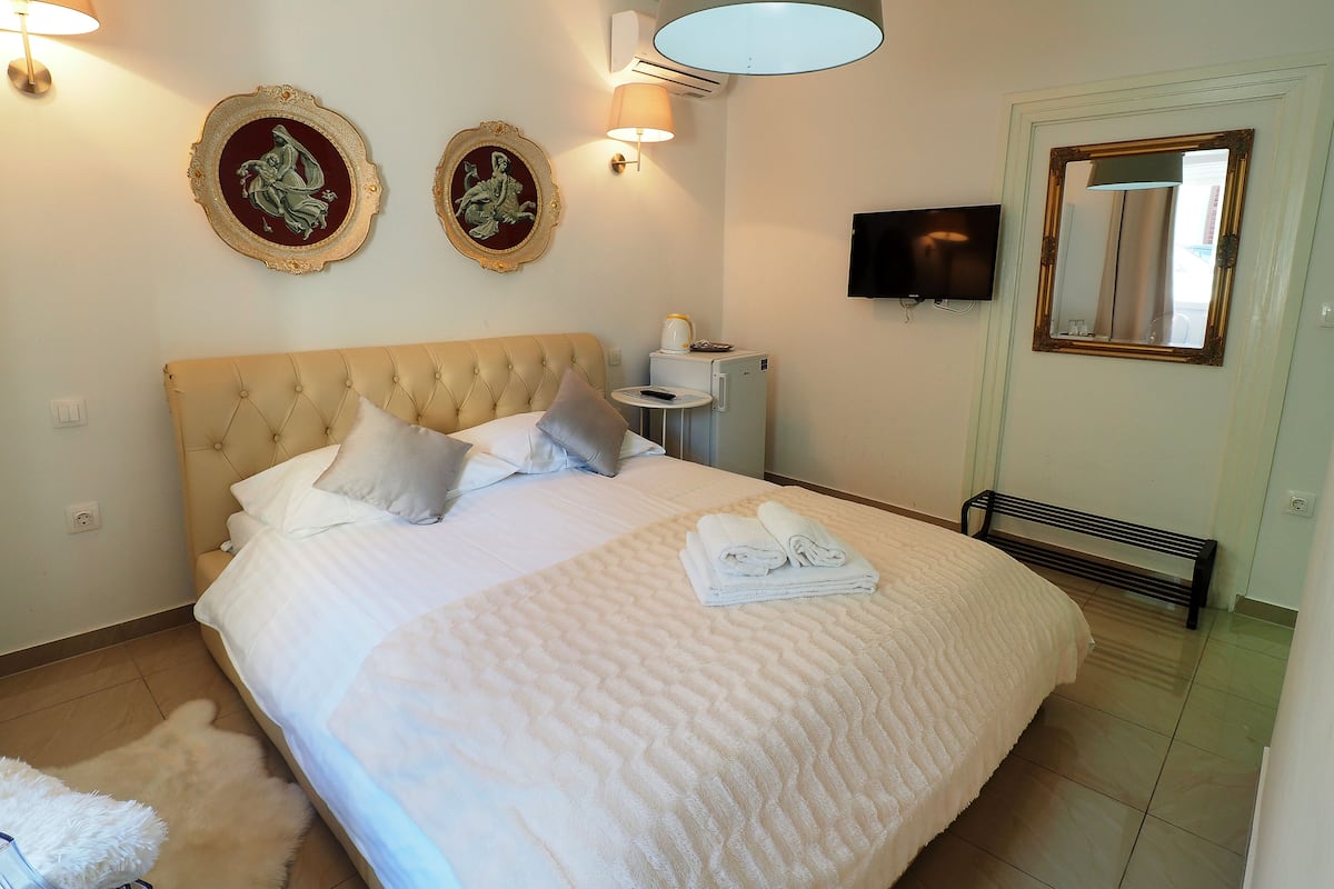 A neatly made bed with pillows, a bedside table with a lamp, and two wall-mounted picture frames.