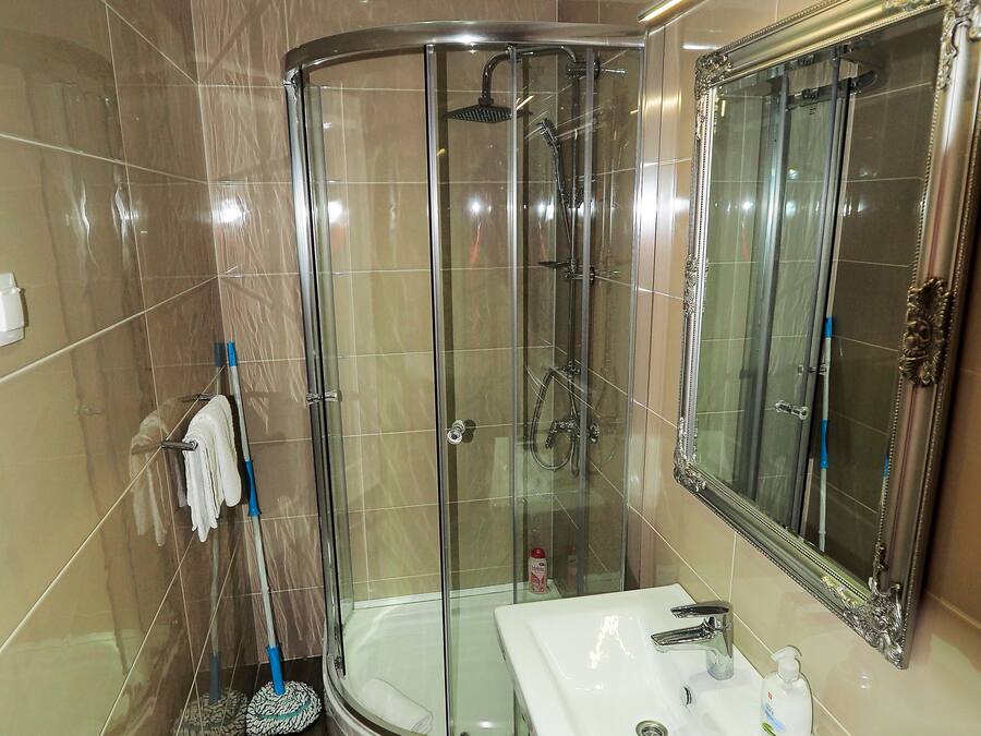 Ein modernes Badezimmer mit einer Duschkabine aus Glas, einem weißen Waschbecken und einem großen Spiegel.