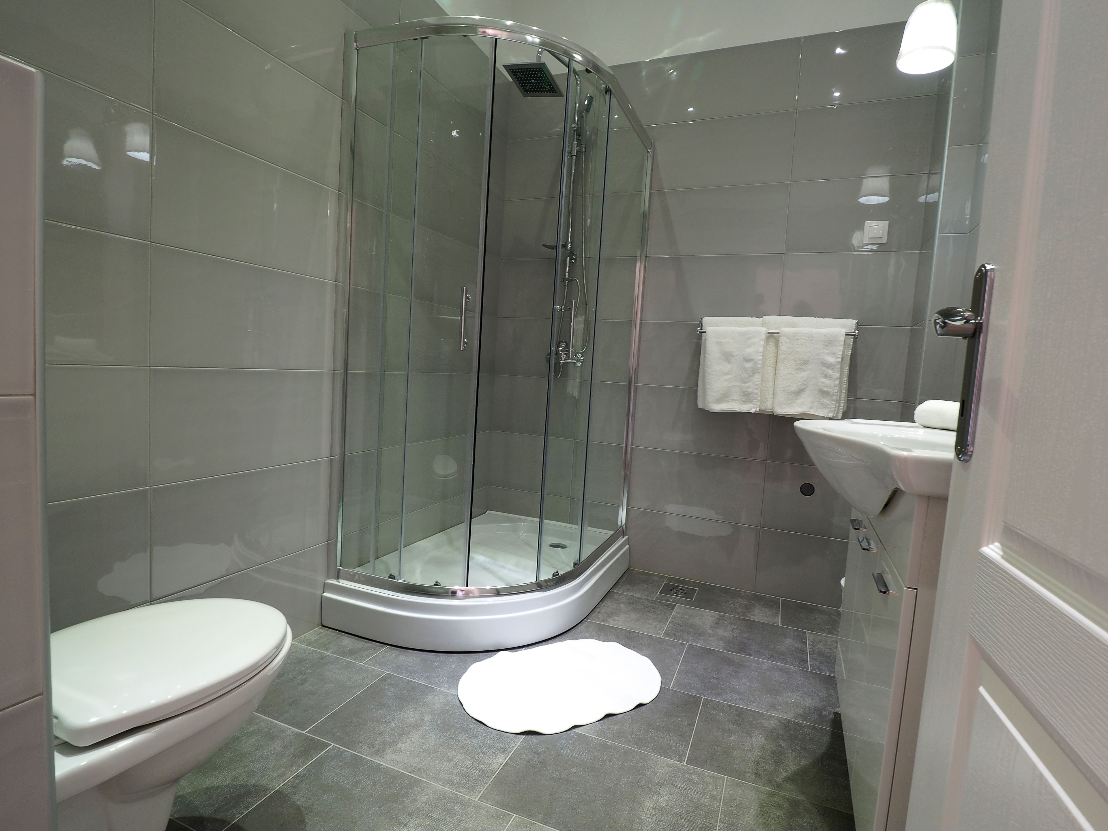 Un baño moderno con cabina de ducha de vidrio, inodoro y lavamanos.