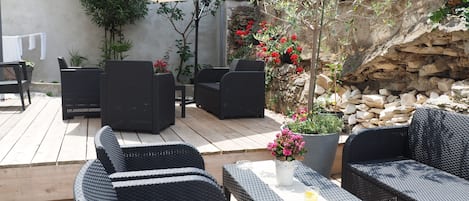 An outdoor patio with wicker furniture, a table with a drink, and a large umbrella.