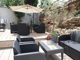 Un patio al aire libre con mobiliario de mimbre, una mesa con una bebida y un paraguas grande.
