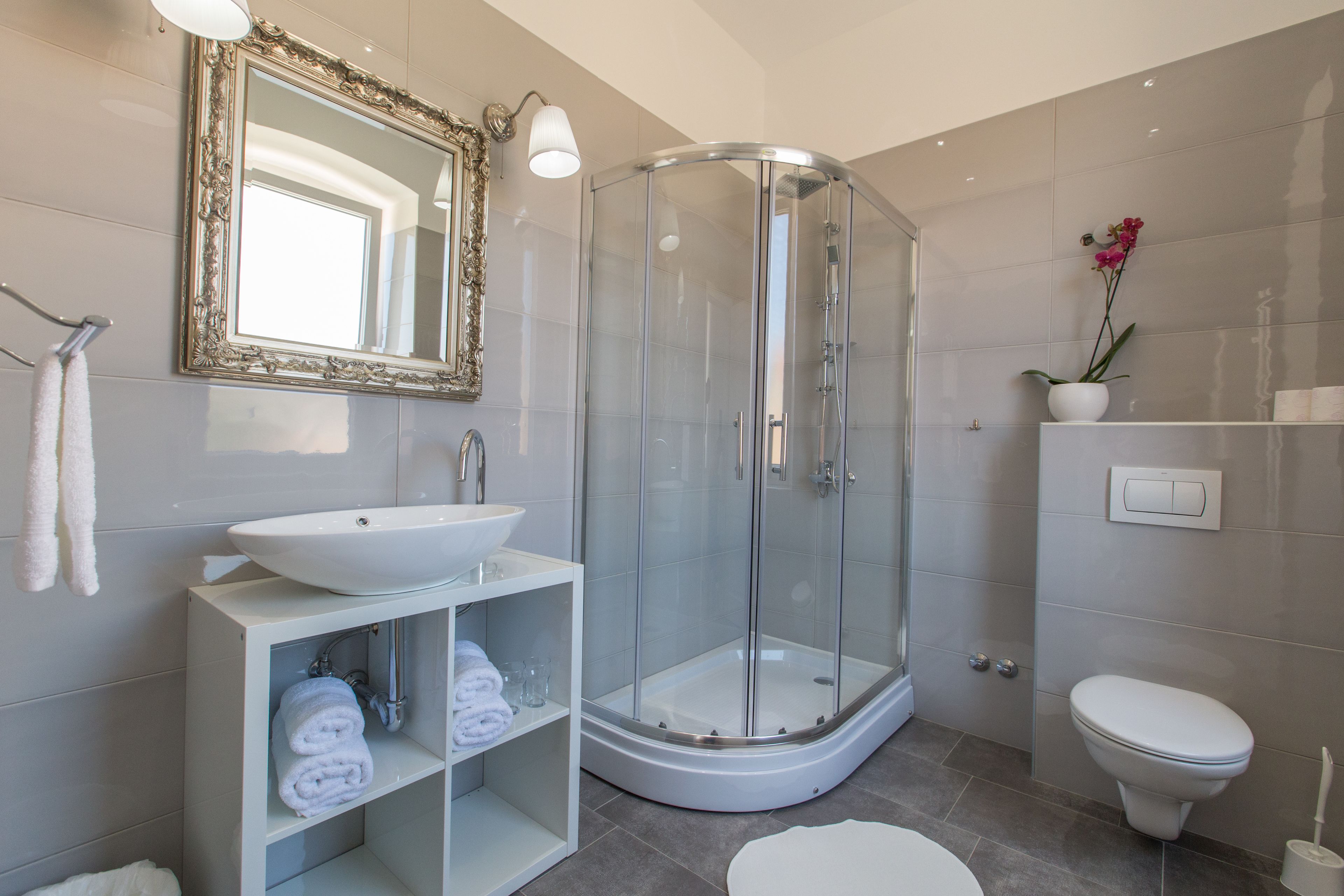 A modern bathroom with a glass-enclosed shower, a white sink, and a toilet.