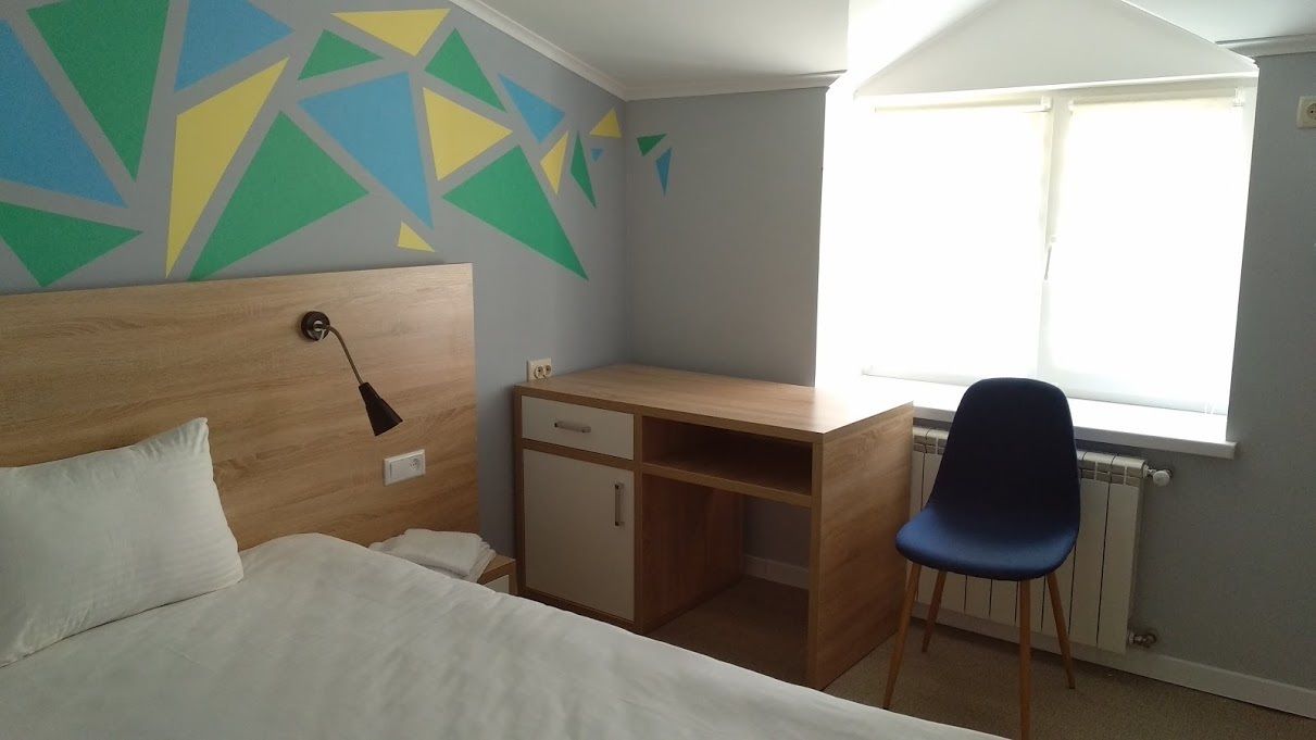 Une chambre à coucher avec un lit, un bureau, une chaise et une fenêtre donnant sur un paysage agréable.