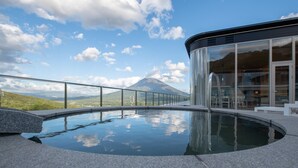 A modern building with a glass facade, a pool, and a mountain view. - Skye Niseko (Kutchan)