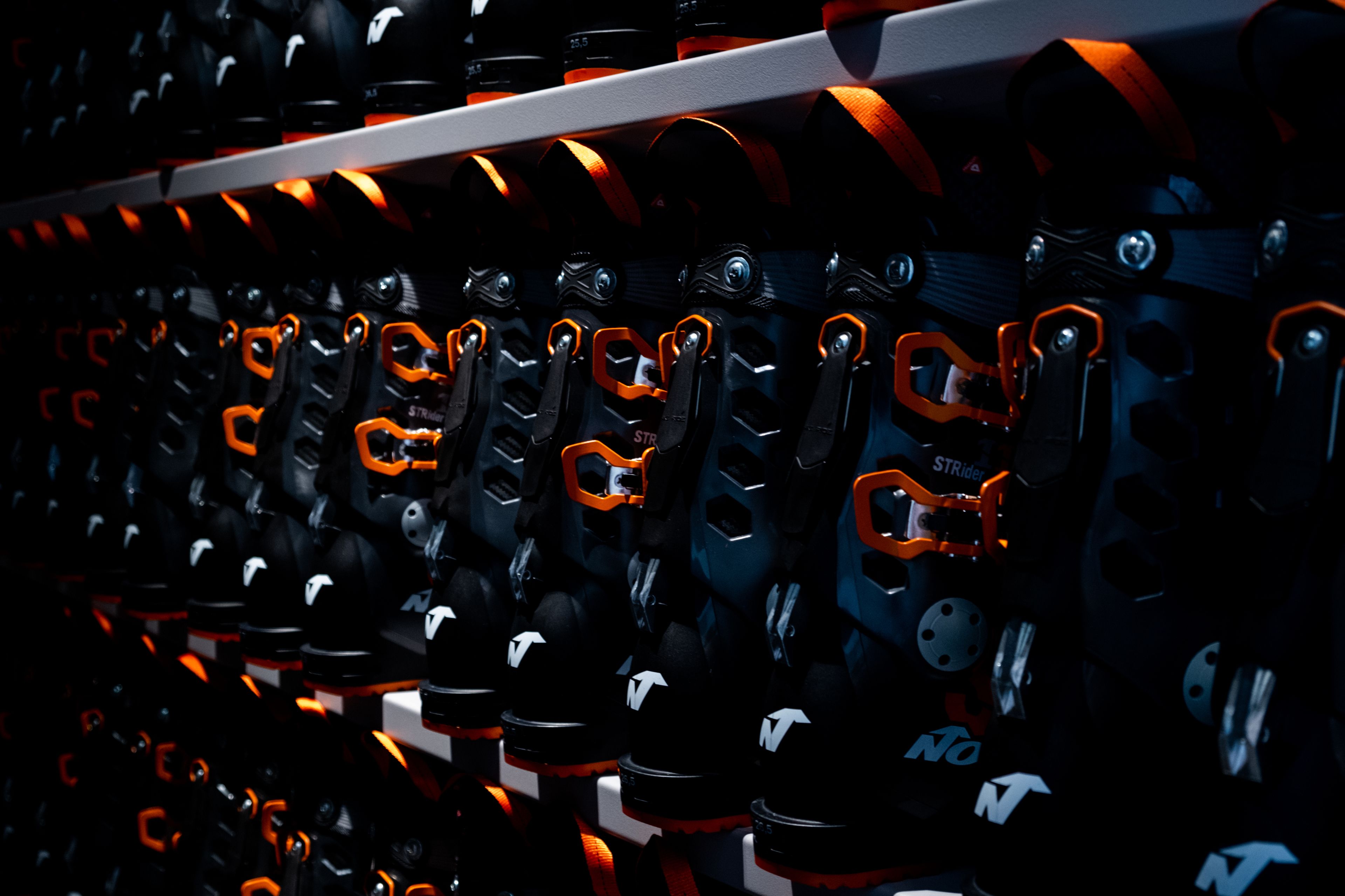 A row of black and orange helmets with visible branding, arranged on a shelf.