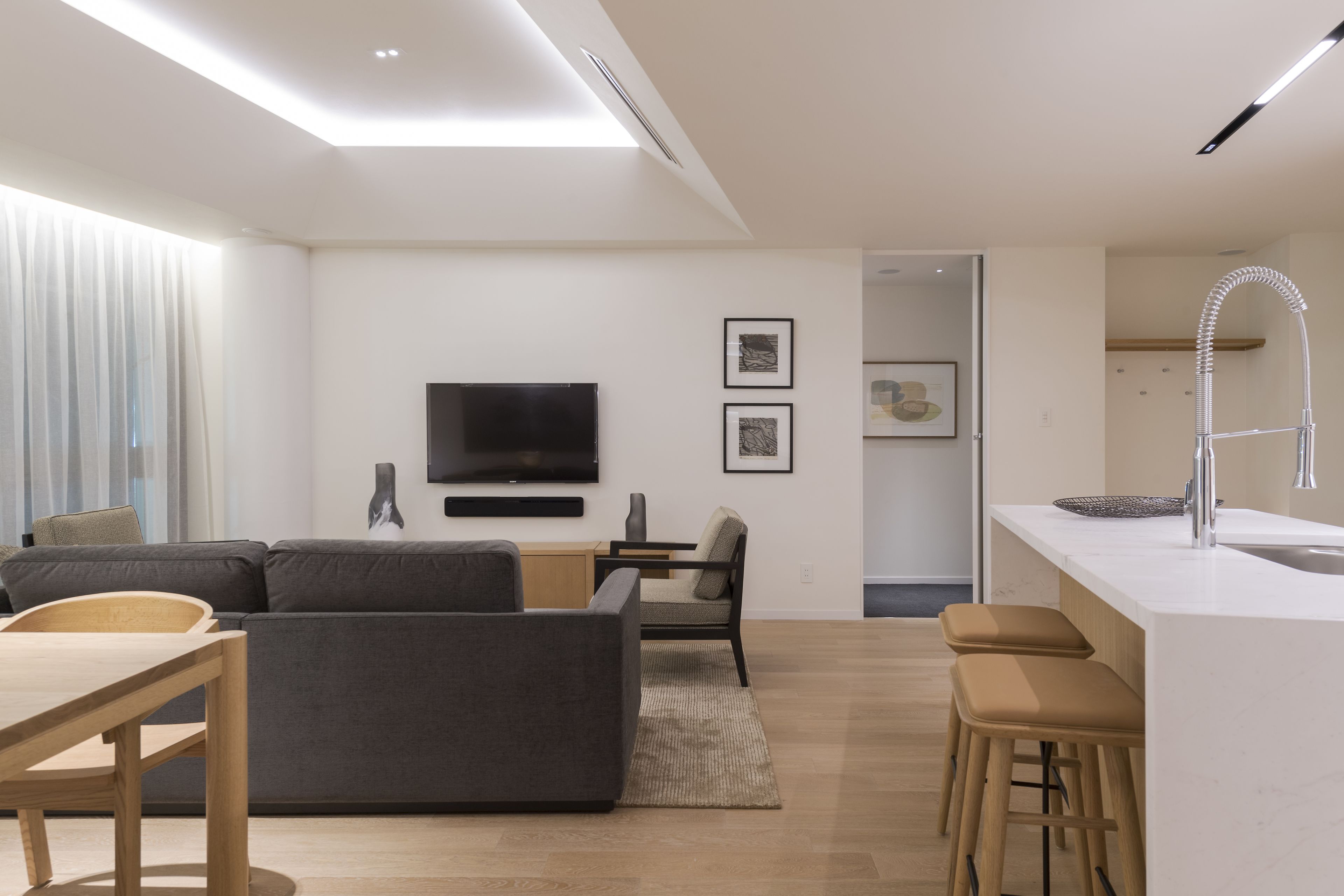 Una sala de estar moderna con un sofá, televisor y una pequeña zona de comedor.