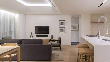 Una sala de estar moderna con un sofá, televisor y una pequeña zona de comedor.