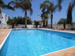 Una piscina al aire libre, sombrillas, sillones reclinables de piscina