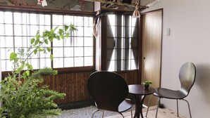 Una habitación con suelo de tatami, un fusuma, una mesa tradicional japonesa y sillas.