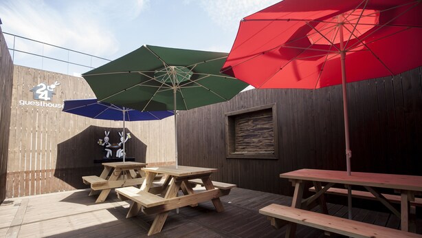 A wooden deck with picnic tables and umbrellas. - 24 Guesthouse Jeonju (Jeonju)