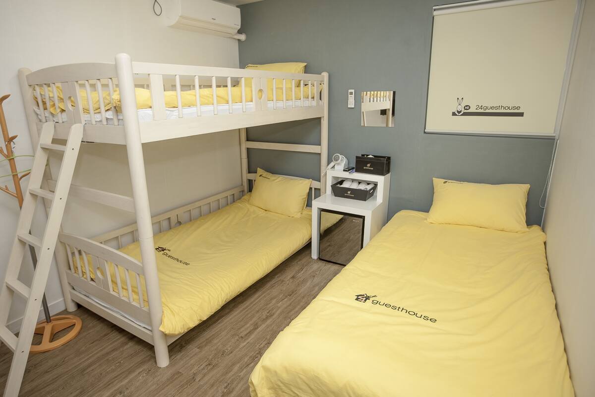 A bunk bed room with yellow bedding and a desk with a lamp.