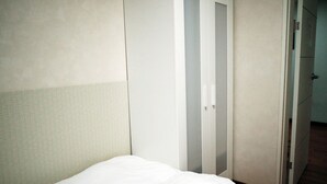 A hotel room with a bed, a wardrobe, and a door leading to another room.