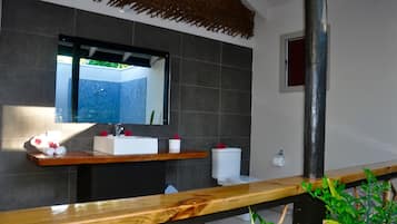 Casa de banho com toucador de madeira, um espelho grande e uma sanita.