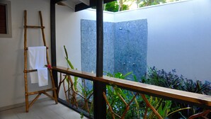 A bamboo ladder with white towels, a wooden railing, and a view of a stone wall and plants. - Coconut Beach Resort (Tavewa Island)