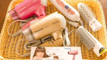 Ein Korbwesenkorb mit verschiedenen Haartool-Accessoires, darunter ein pinkfarbener Föhn, eine weiße Haarbürste und ein beige-farbener Föhn.
