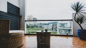 Un balcon avec une chaise en osier, une table en fibres tressées et une plante en pot.