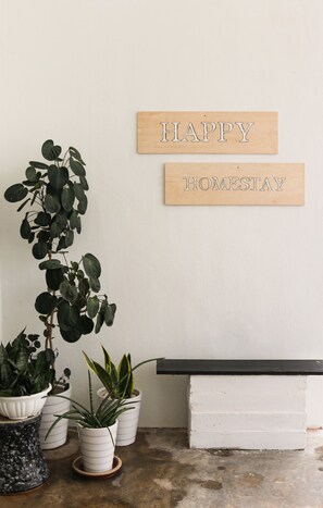 A wall with two wooden signs that read "HAPPY HOMESTAY" and a potted plant arrangement.