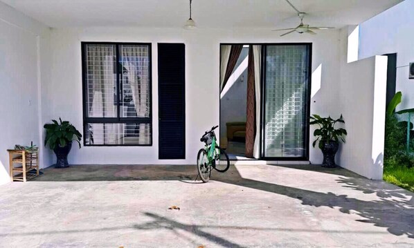 A covered outdoor area with a concrete floor, a bicycle, and potted plants.