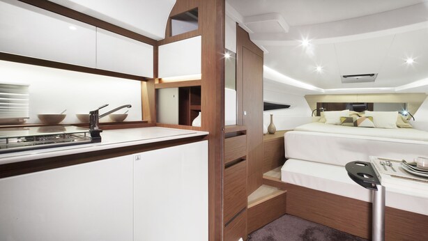 Un intérieur moderne et compact comprenant un coin cuisine, un lit avec une tête de lit et un espace repas.