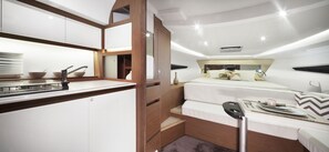 A compact, modern interior with a kitchenette, a bed with a headboard, and a dining area. - Vietyacht Marina Club - Halong Bay Cruise (Tuan Chau)