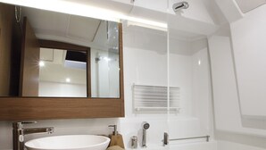 Une salle de bain moderne avec un grand lavabo blanc, un miroir au-dessus et un espace douche.