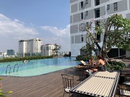 A rooftop pool with clear blue water, surrounded by lounge chairs and a wooden deck.