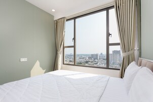 A hotel room with a large window, a bed with white bedding, and curtains.