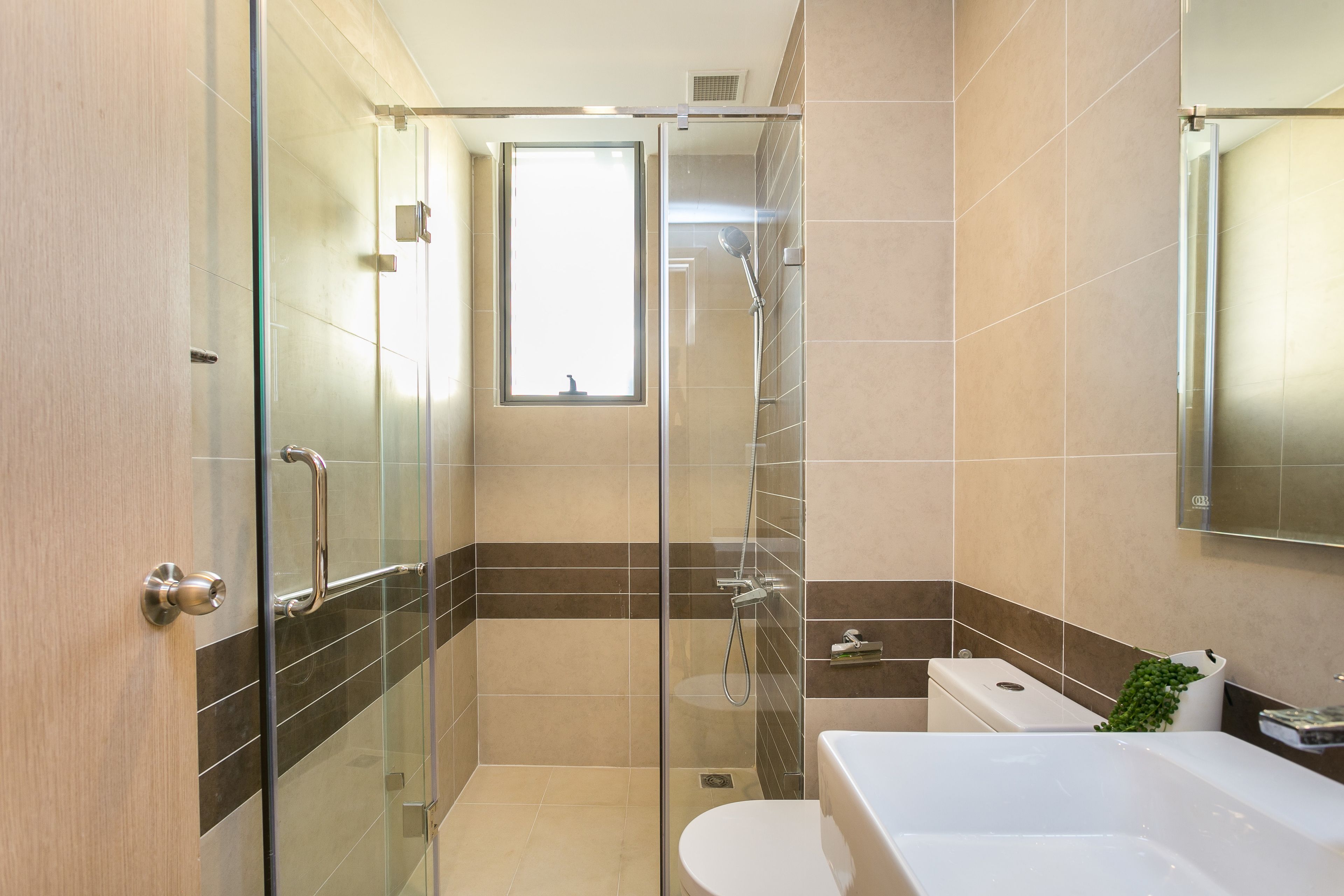 A modern bathroom with a glass-enclosed shower, a toilet, and a bathtub.