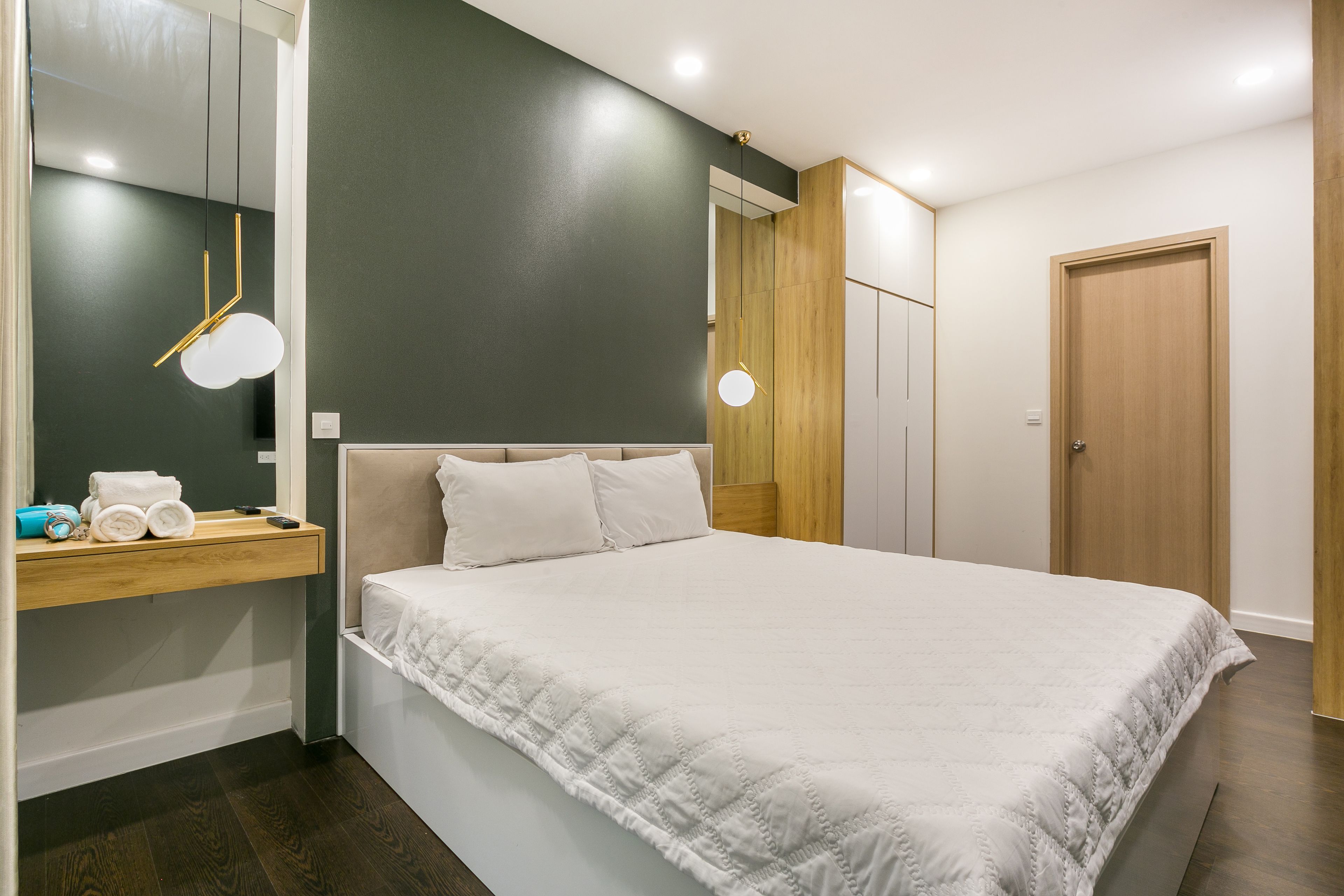 Un dormitorio moderno con una cama grande, una mesita de noche de madera, un espejo y un armario.