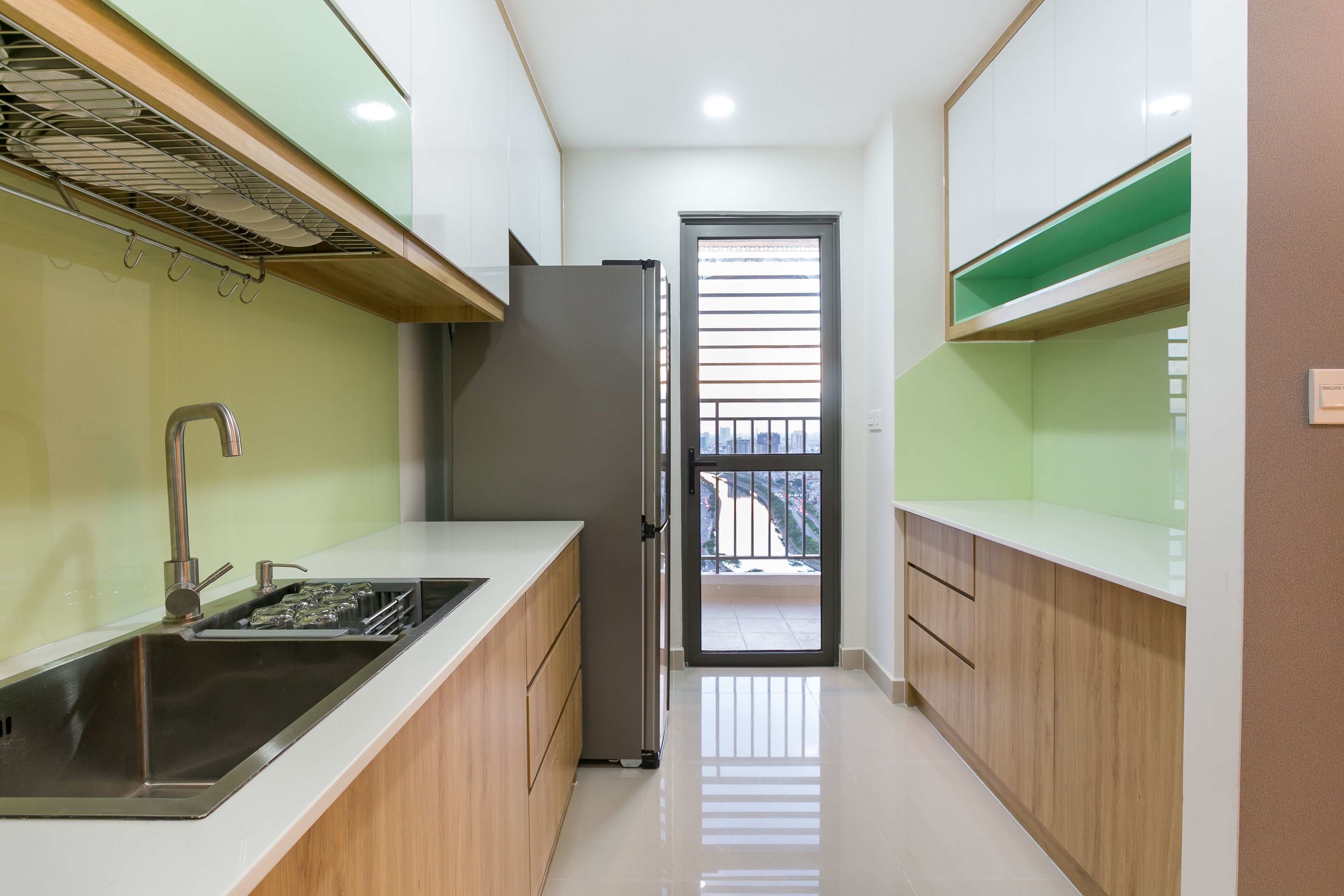 Una cocina moderna con un lavamanos de acero inoxidable, armarios de madera y un refrigerador empotrado.