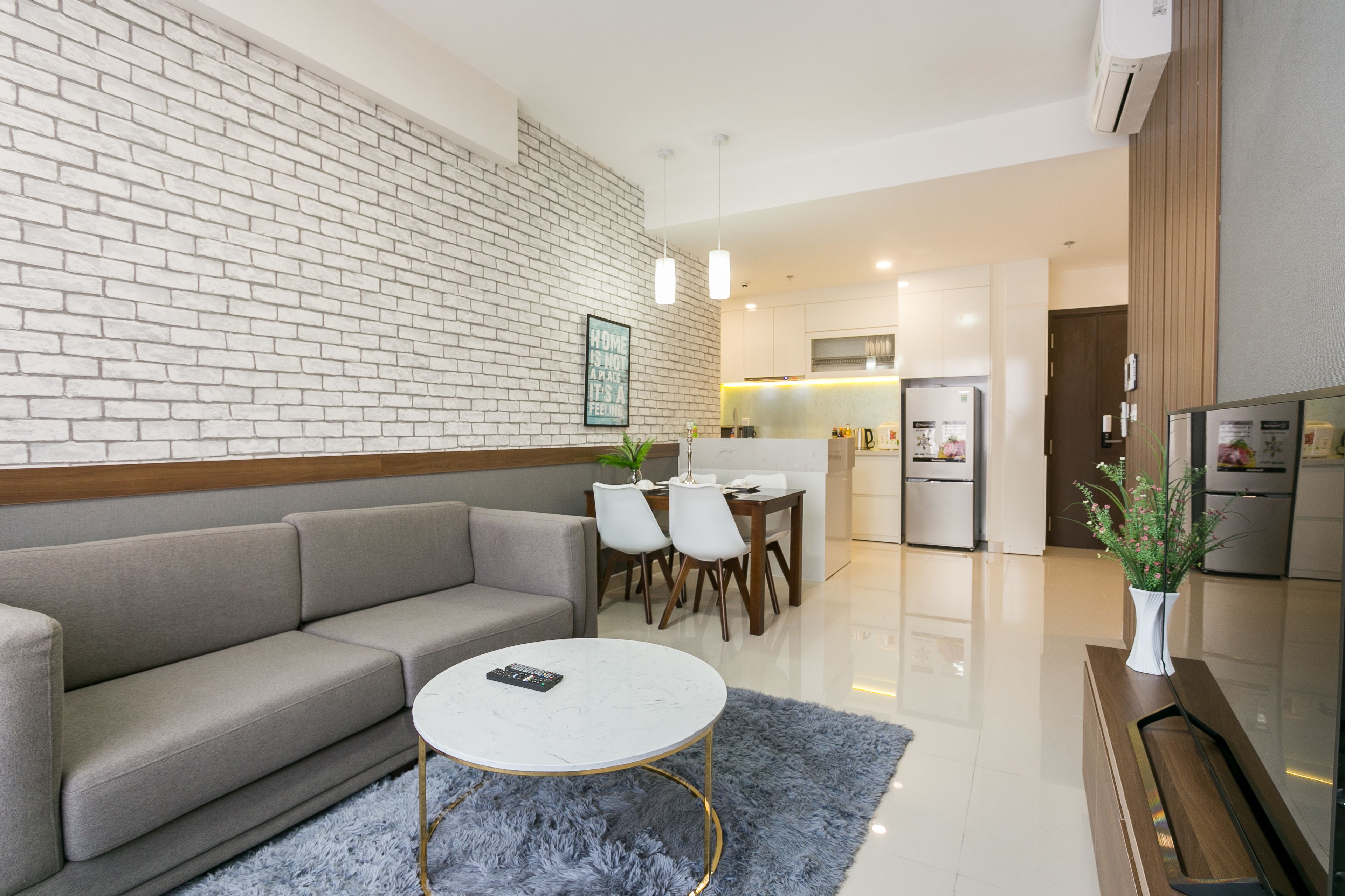 A modern living room with a grey sofa, a round coffee table, and a blue rug.