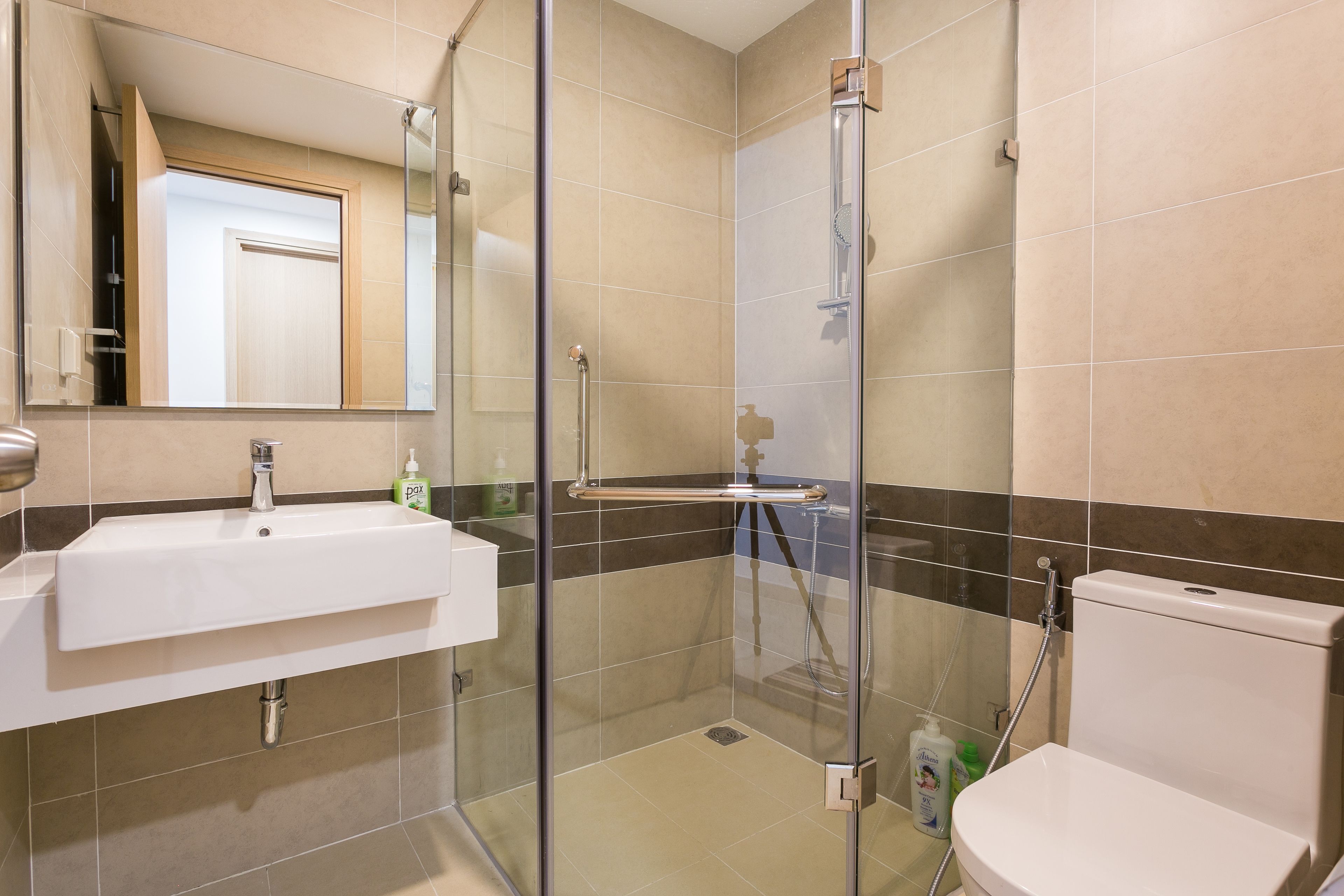 Un baño moderno con ducha de vidrio, lavamanos blanco y retrete.