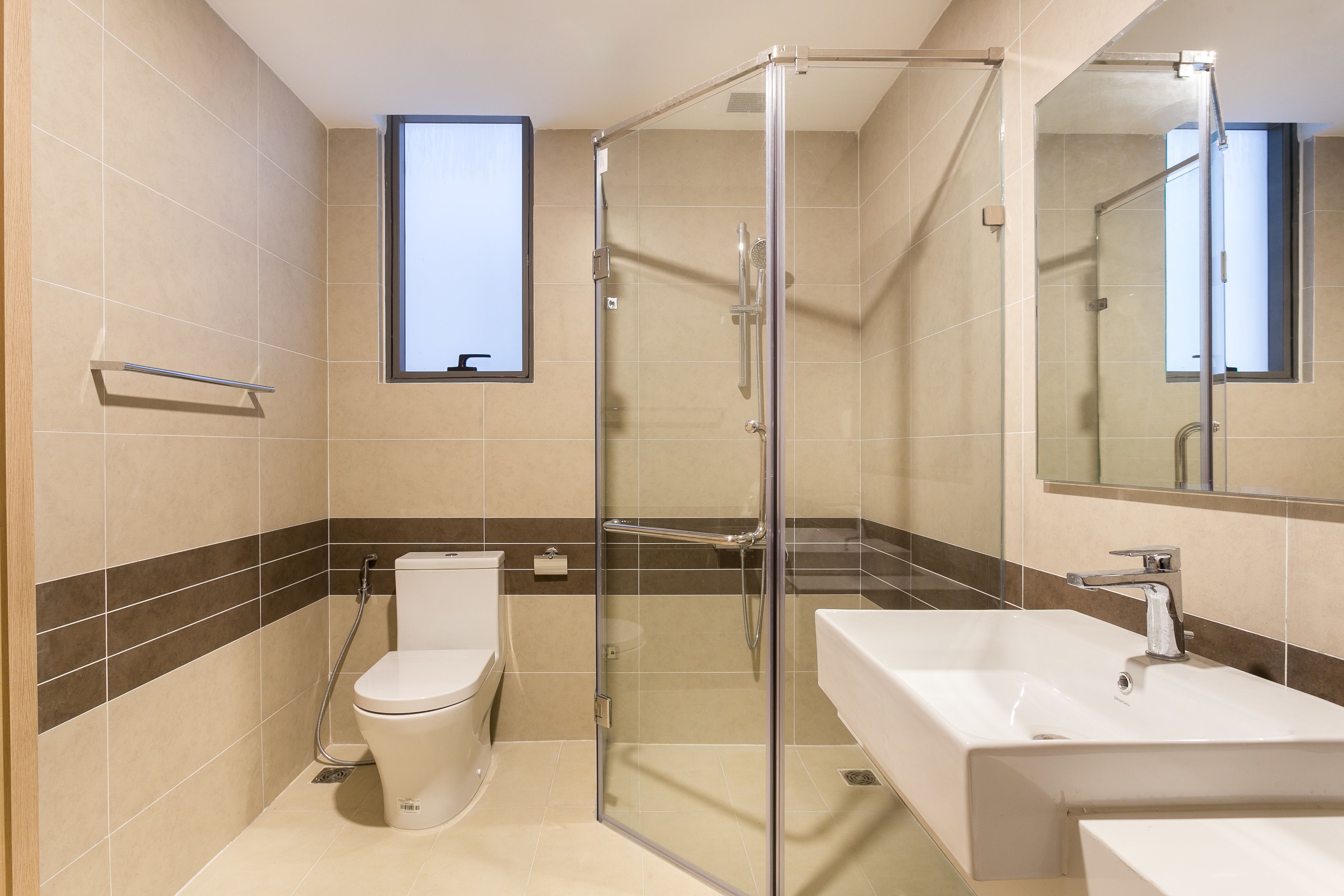 A modern bathroom with a glass-enclosed shower, a toilet, and a sink.