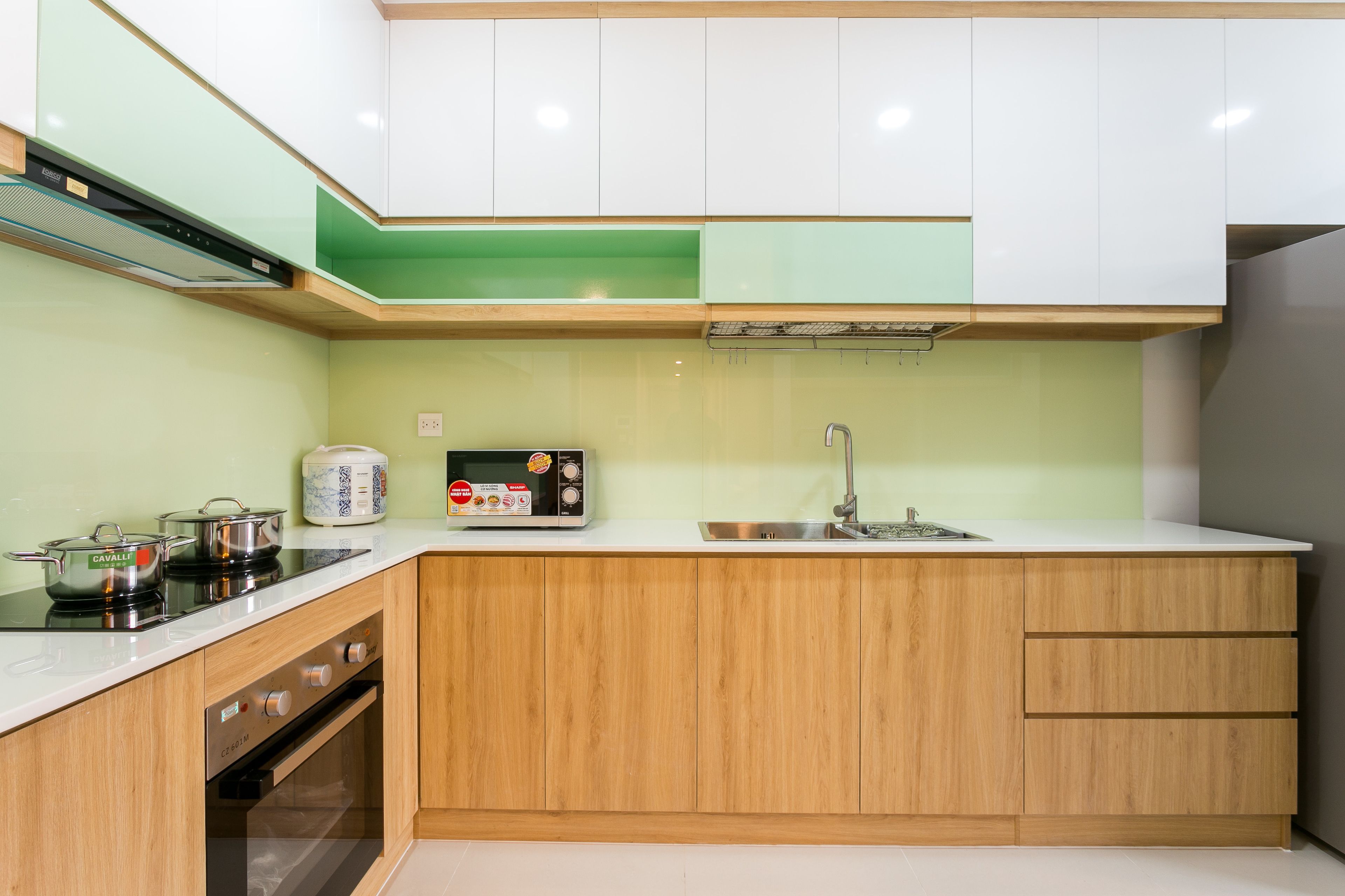 A compact kitchen with white cabinets, a stainless steel sink, and a microwave.