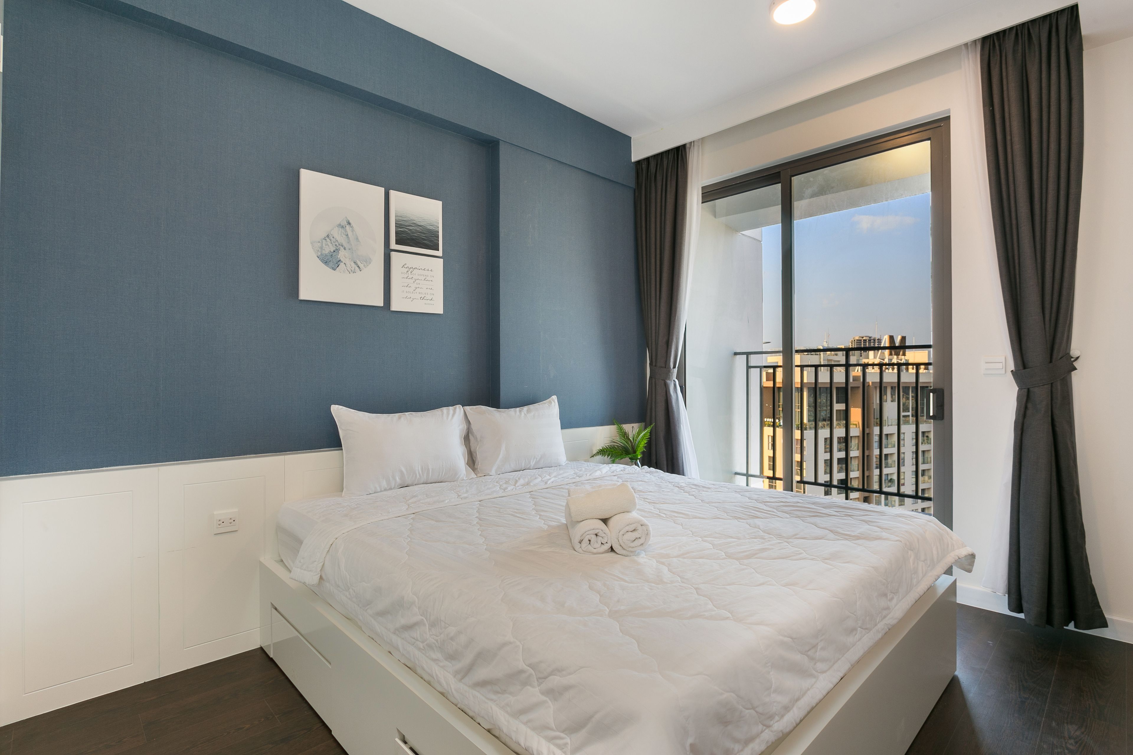 A bedroom with a large bed, a view of a balcony, and a blue wall.