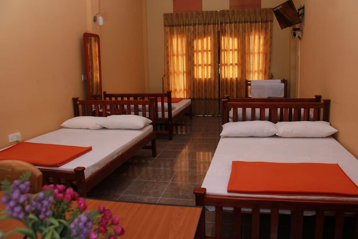 Una habitación de hotel con dos camas individuales, una mesa de madera y una silla.