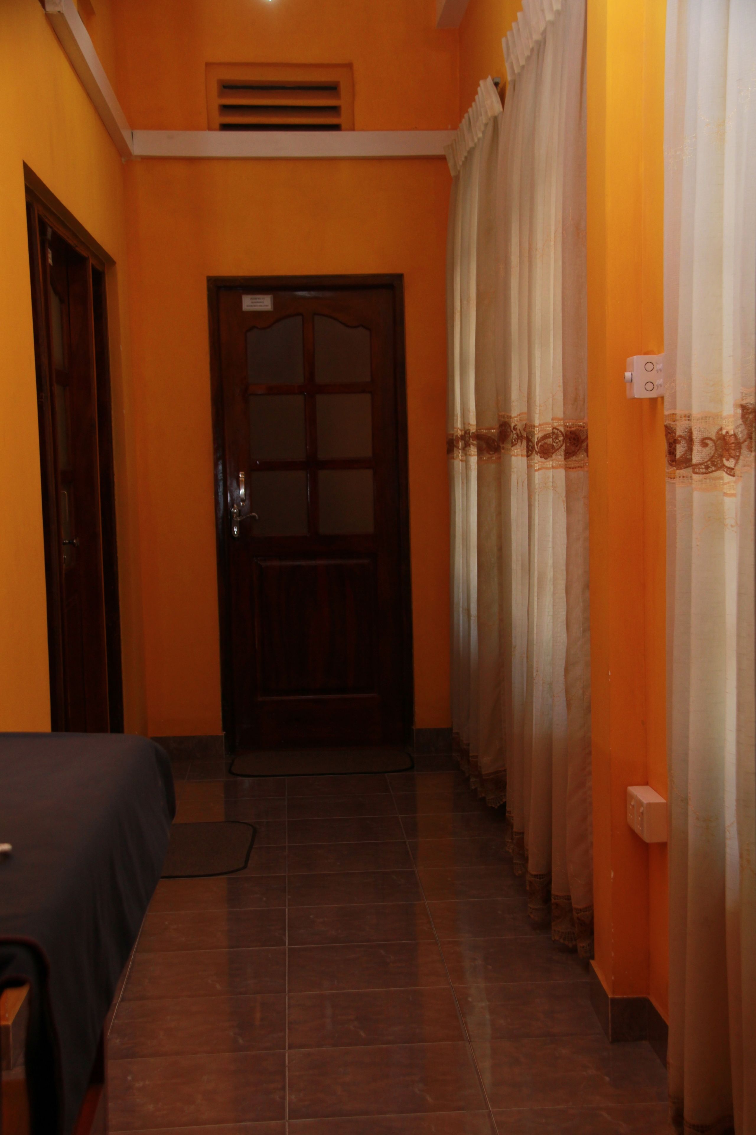 A hallway with a door, a bed, and curtains.