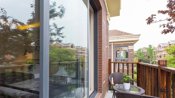 Un balcon avec des fauteuils en osier, une petite table et un pot de fleurs.