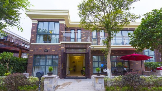 Un edificio de dos plantas con fachada de ladrillo, ventanas amplias y un balcón.