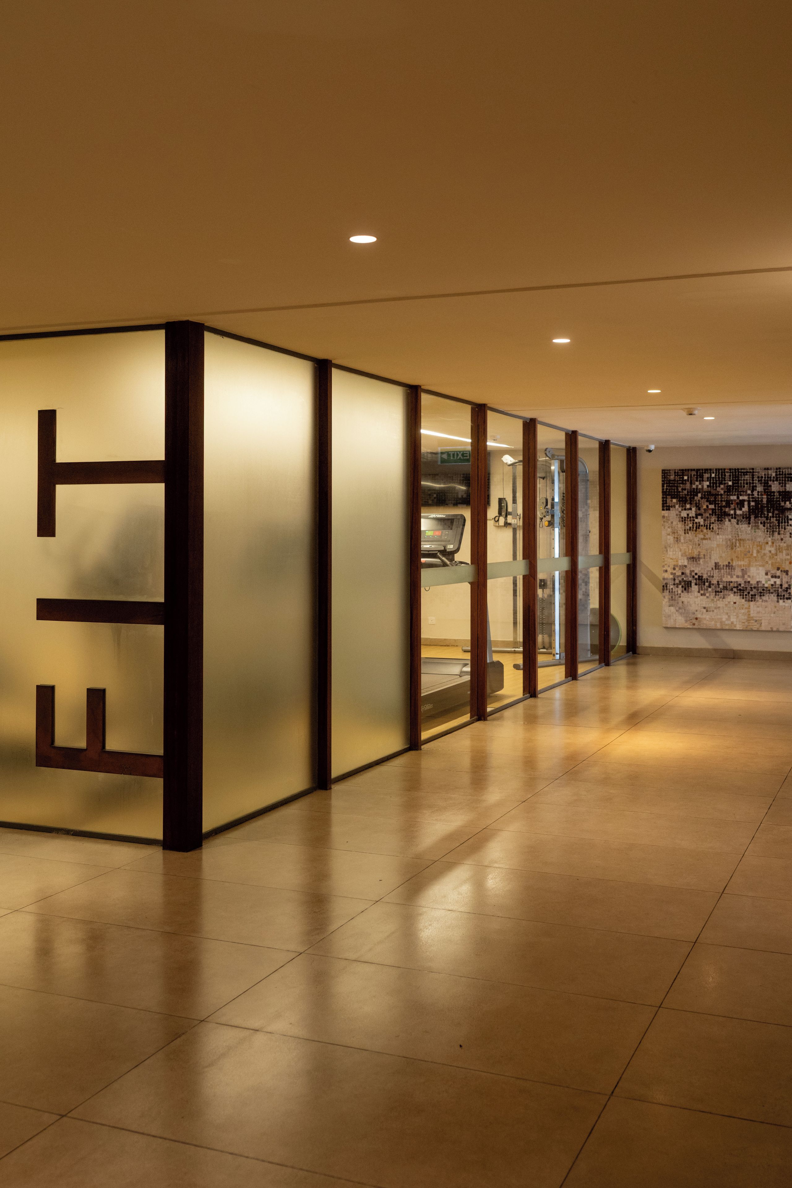 Un corridoio dal design moderno, con un'ampia insegna illuminata con le lettere 'EIT' e una parete divisoria in vetro che include un tapis roulant.