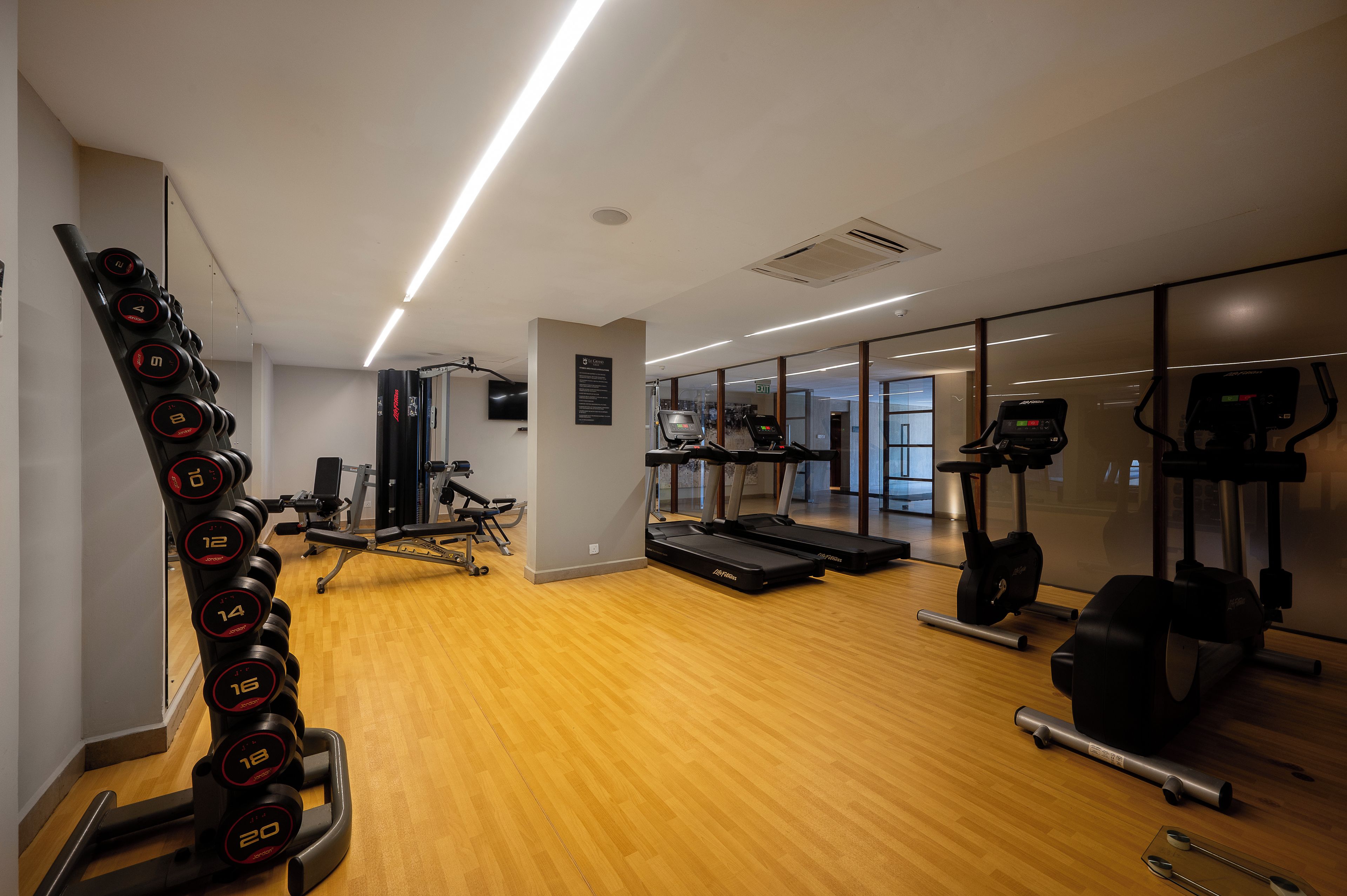 Un gimnasio con equipo de ejercicio, una cinta de correr y un espejo.