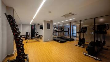 Un gimnasio con equipo de ejercicio, una cinta de correr y un espejo.