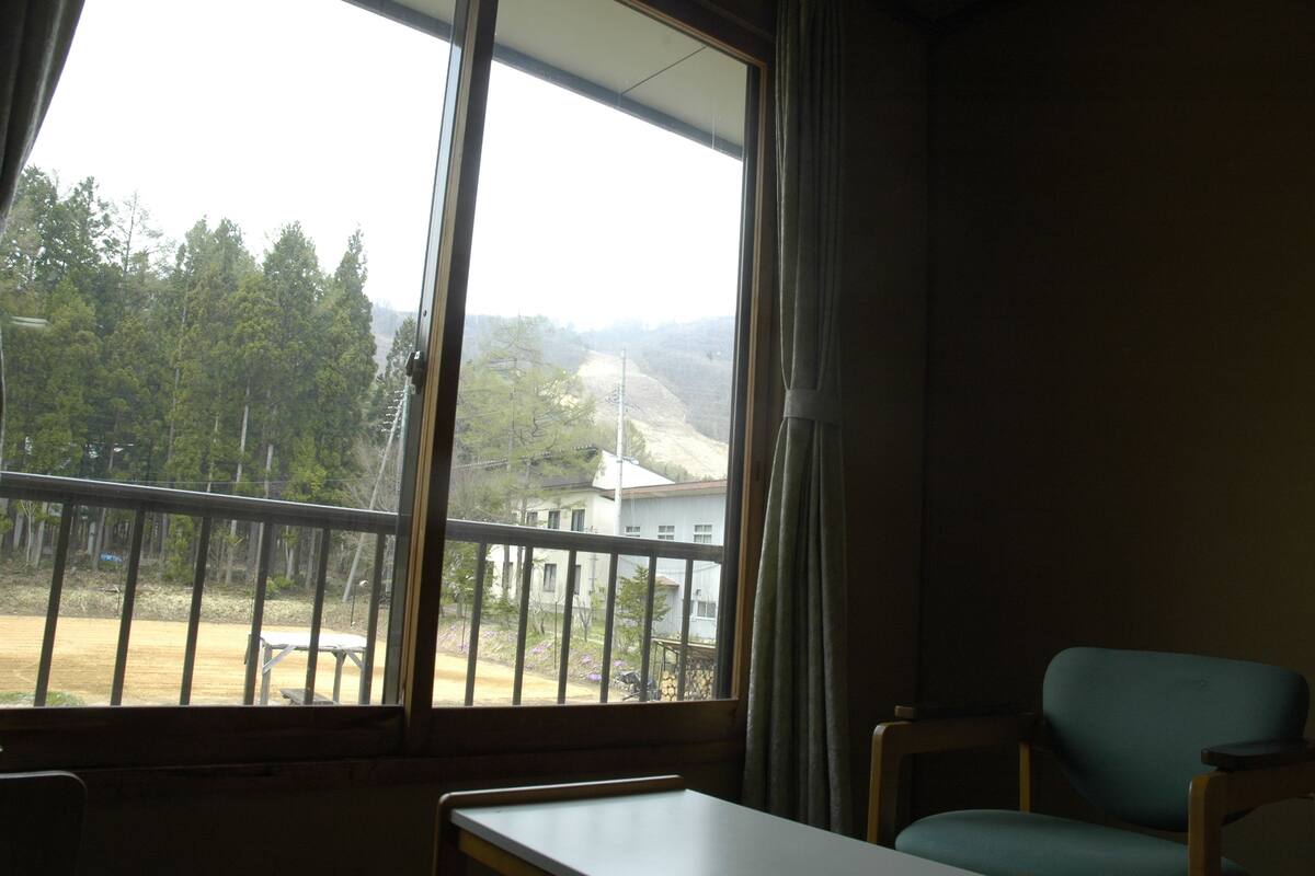 A room with a large window, a table, and a chair.