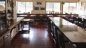 Ein Restaurant mit einem langen Gemeinschaftstisch, Holzstühlen und einem gefliesten Boden.